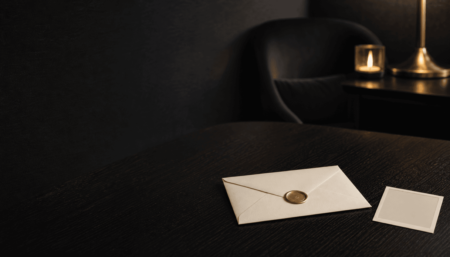 A sealed envelope with a wax seal beside a face-down photograph on a dark wood table.