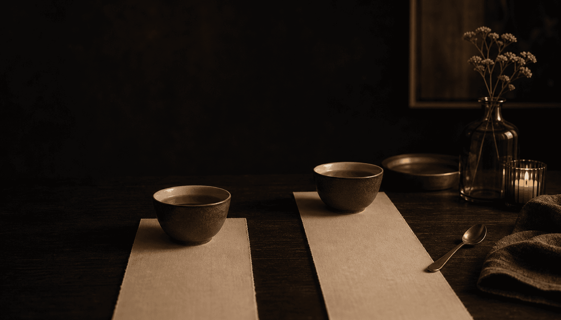 Two cups of tea on a dark wood table in warm lamplight.
