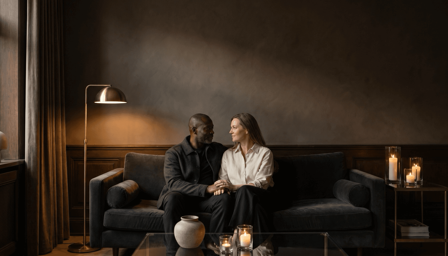 A couple sitting close together in a warm, quiet charcoal room.