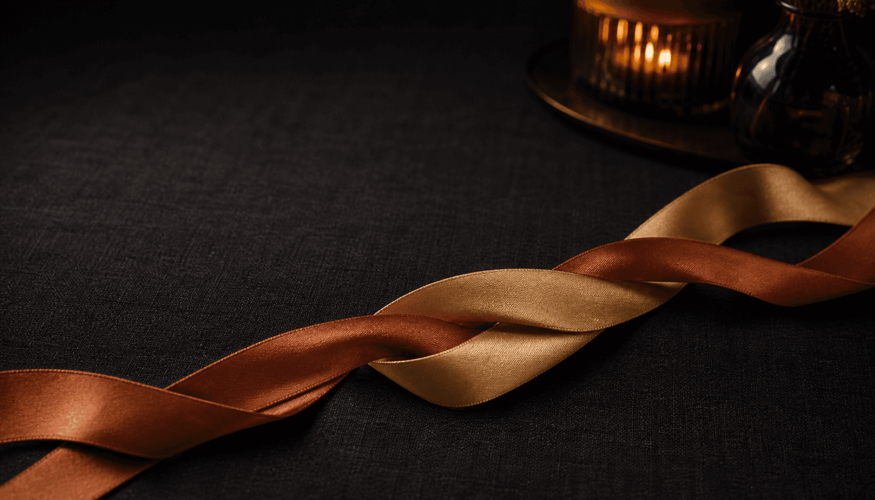 Two intertwined ribbons of different colors on a warm charcoal background.
